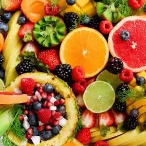 Colorful flat lay of assorted tropical fruits including pineapple, berries, and citrus.